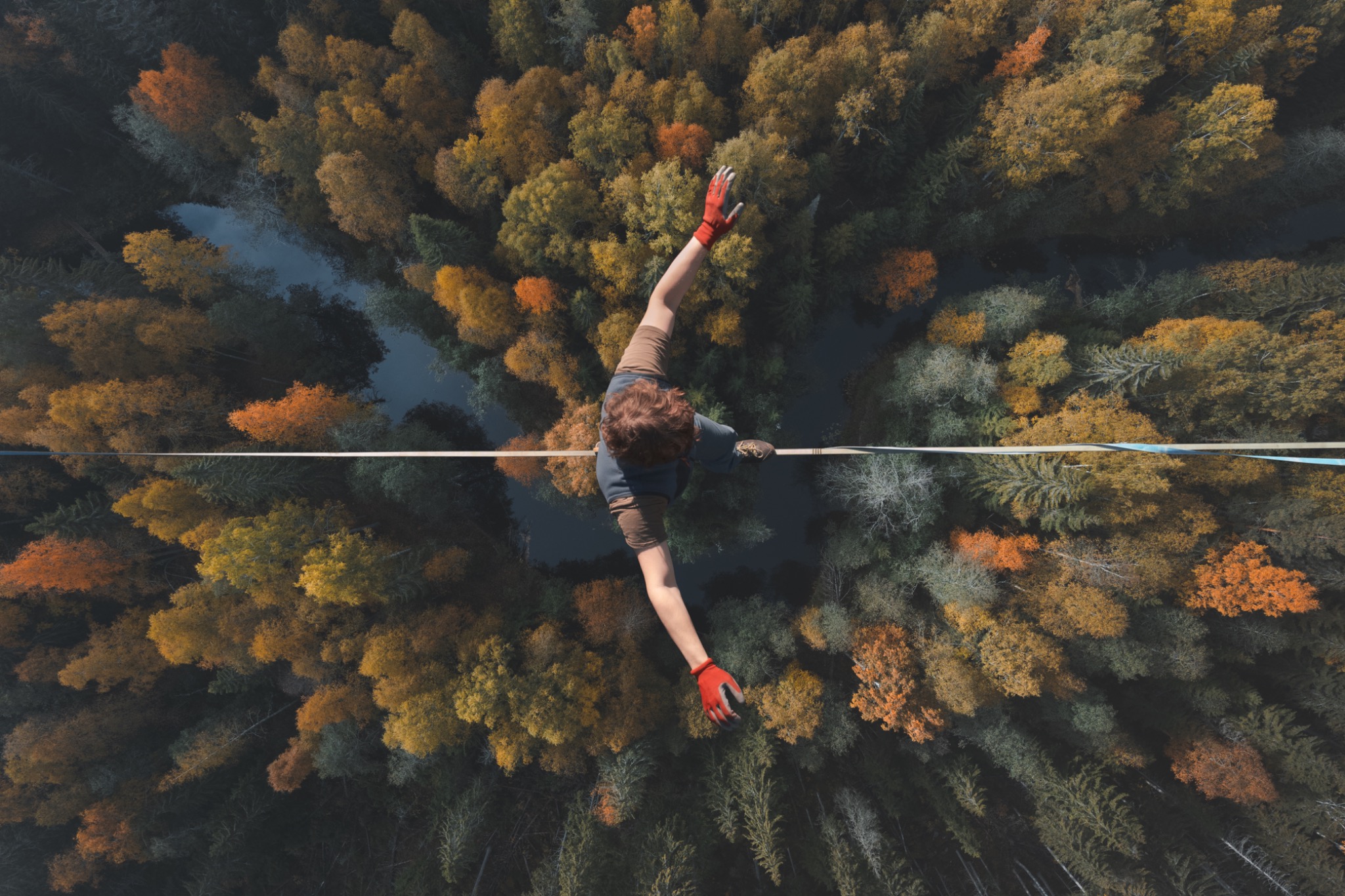 Ein Mensch balanciert auf einer Slackline hoch über einem herbstlichen Wald – Sinnbild für den schmalen Grat zwischen Missverständnis und Konflikt